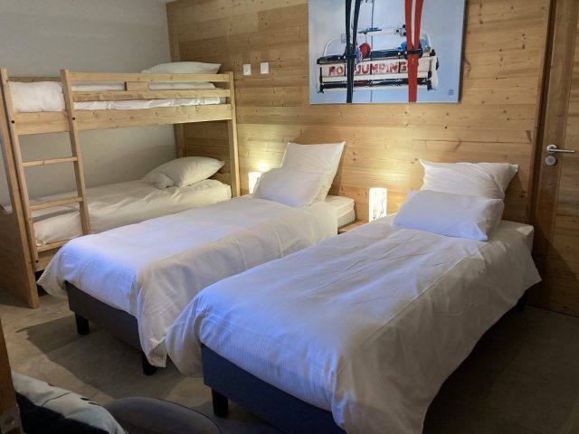 Chambre avec un lit superposé et deux lits simples